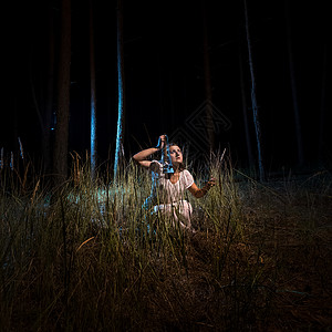 穿着睡衣的年轻女晚上坐在高森林里带着灯笼图片