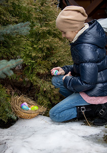 小女孩跪在树旁拿复活节蛋图片