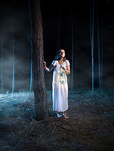 不跟陌生人走害怕的年轻女青在雾的夜间森林中走着灯笼背景