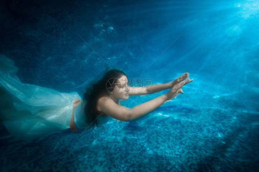 水下射出的美女穿着衣服从光束的泳池上冒出来图片
