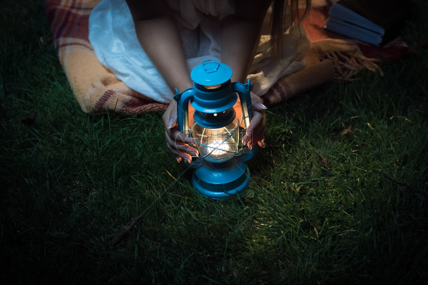 近距离拍摄晚上坐在草地握着灯笼的女子图片