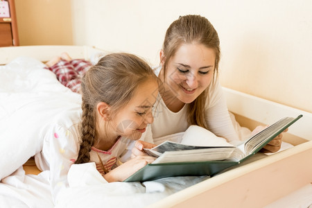 母亲在床上给女儿读大老书的肖像图片