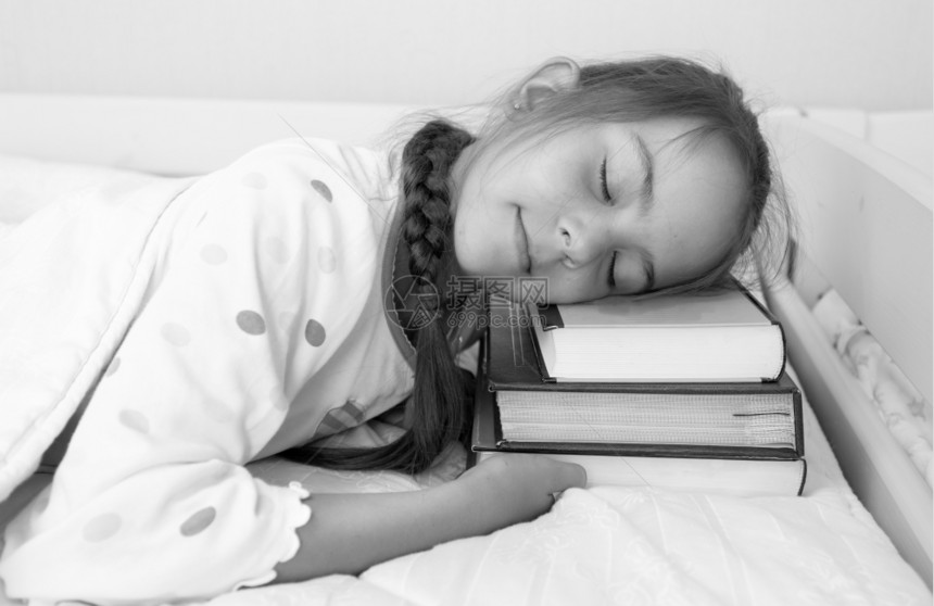 睡在床上的一堆书小女孩的黑白画像图片