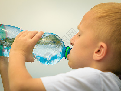 小男孩在户外用塑料瓶子喝水图片