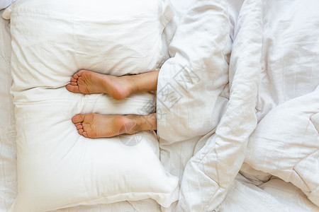躺在床上软白色枕头的双脚近视图片