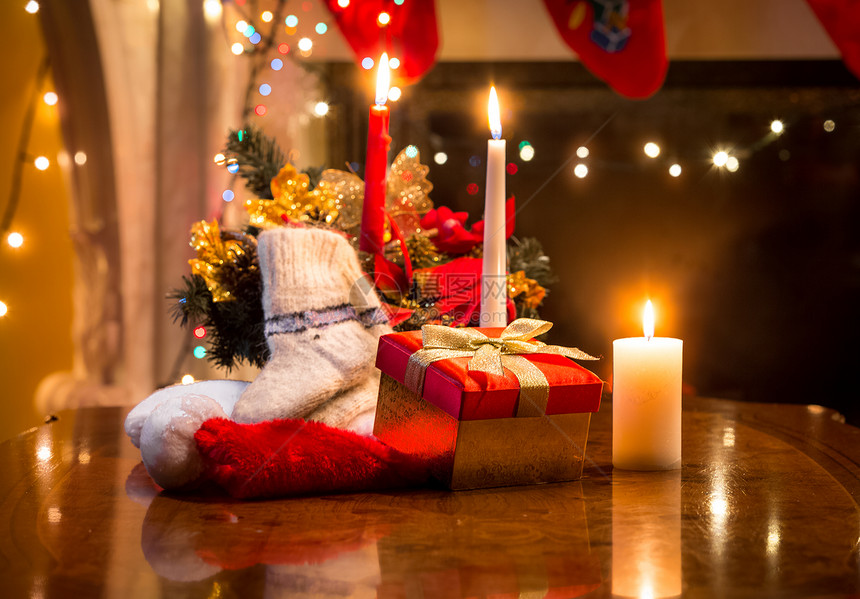 将圣诞蜡烛礼品盒和羊袜放在壁炉的桌上图片