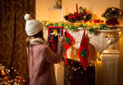 可爱的小女孩在数字平板电脑上拍摄了装饰圣诞壁炉的照片图片