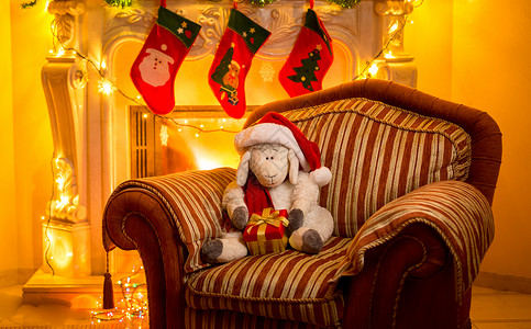 圣诞节在壁炉坐椅子上的玩具羔羊内部照片图片