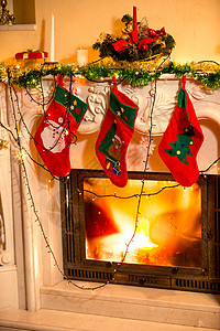 三只圣诞丝袜挂在装饰的壁炉上图片