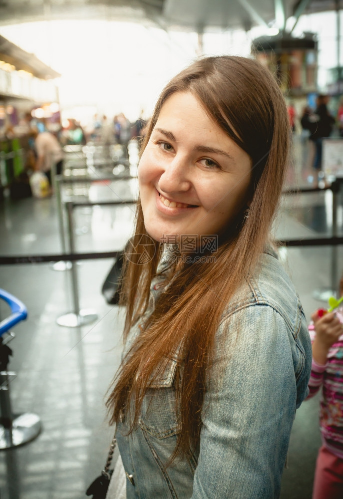 在机场排队时站着微笑的黑发女人近视肖像图片