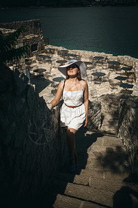 穿着帽子的年轻优雅女在海边城堡走石楼梯上图片