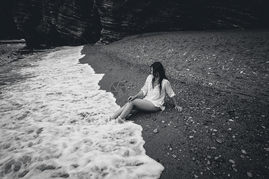 身着白衬衫的年轻女子躺在海滨的黑白照片图片