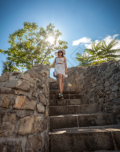 戴白帽子的年轻美女在阳光明媚的白天从石头楼梯上走下图片