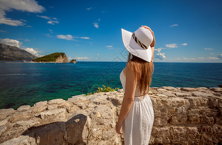 美丽的年轻女子站在海上边看着的岛屿图片