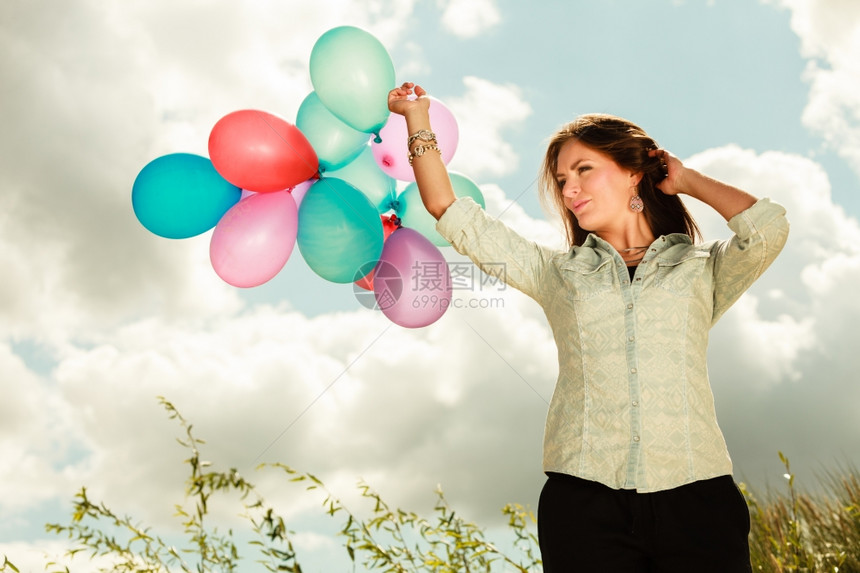 节日庆和生活方式概念具有吸引力的女模特在云层背景外持有一连串多彩气球图片