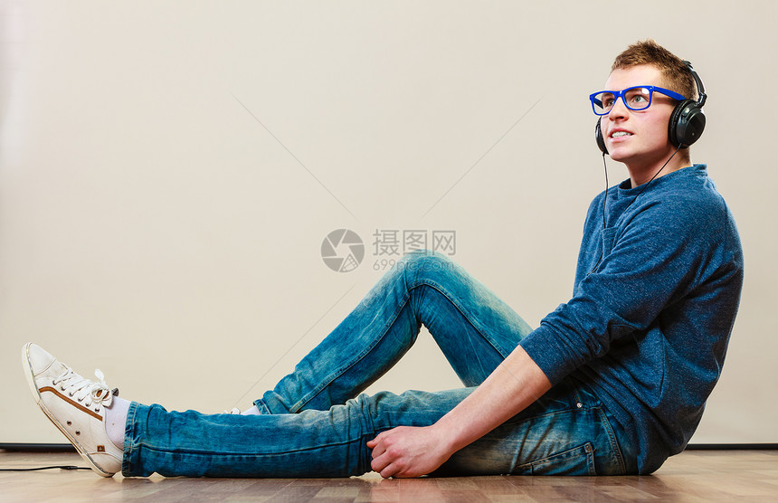 年轻时装男耳机坐在地板上听音乐图片