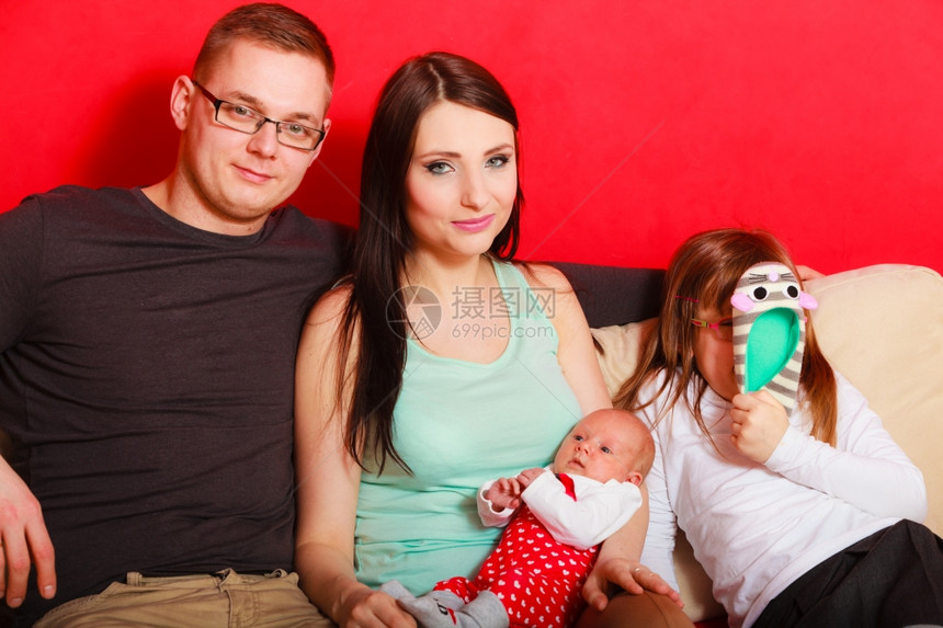 幸福的家庭坐在沙发上看着镜头图片