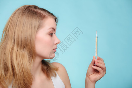 高温的女人发烧病检查蓝色的汞温度计图片