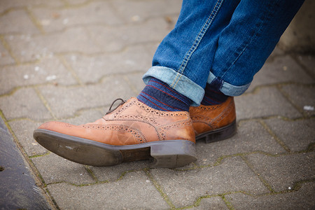 秋季时装脚穿鞋露在外面街上穿牛仔裤和靴子脱袜的男腿高清图片