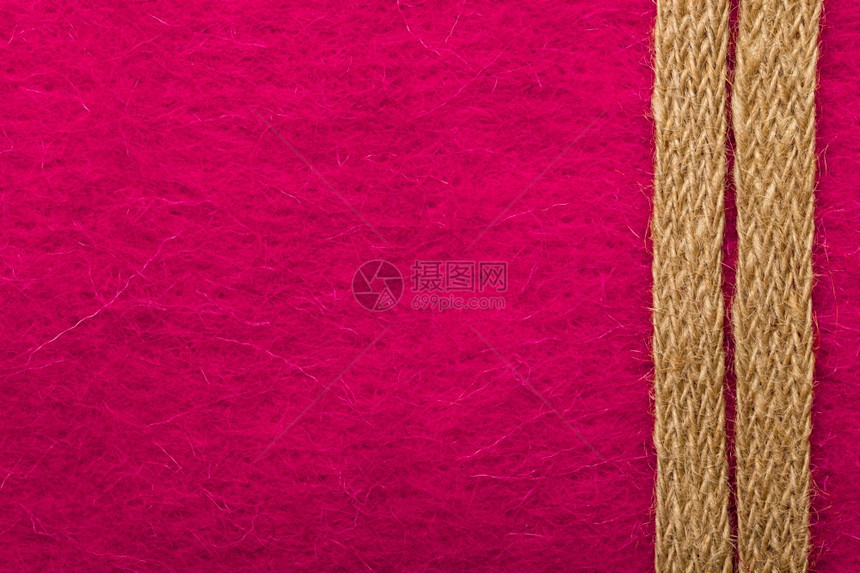 由粉红色纺织品背景上粗糙的绳形成边框或架图片
