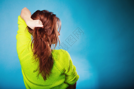 年轻女孩拉着她的长棕色头发蓝后视图片