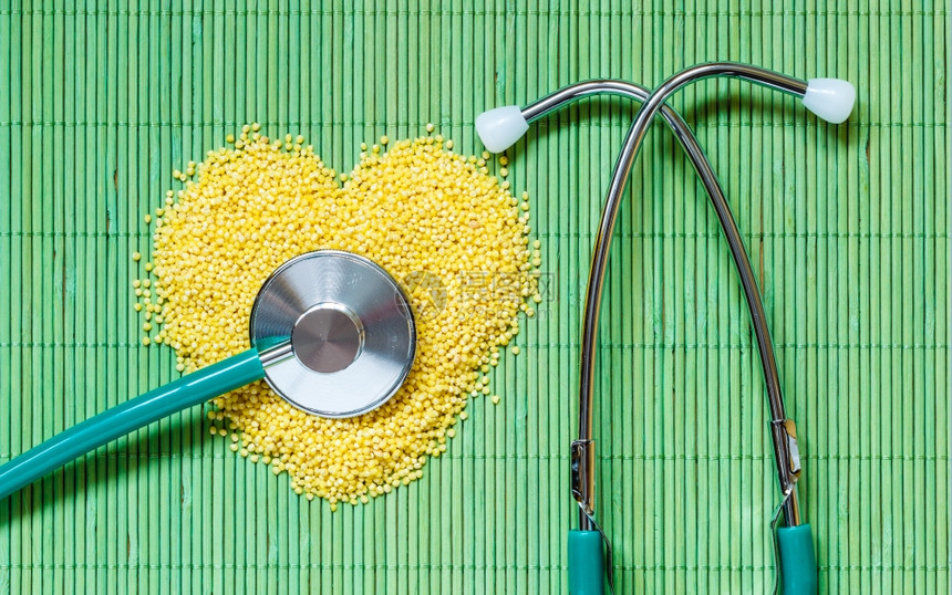 健美的生活概念小米呻吟心脏形状和听诊器在绿垫表面健康食物帮助降低胆固醇图片