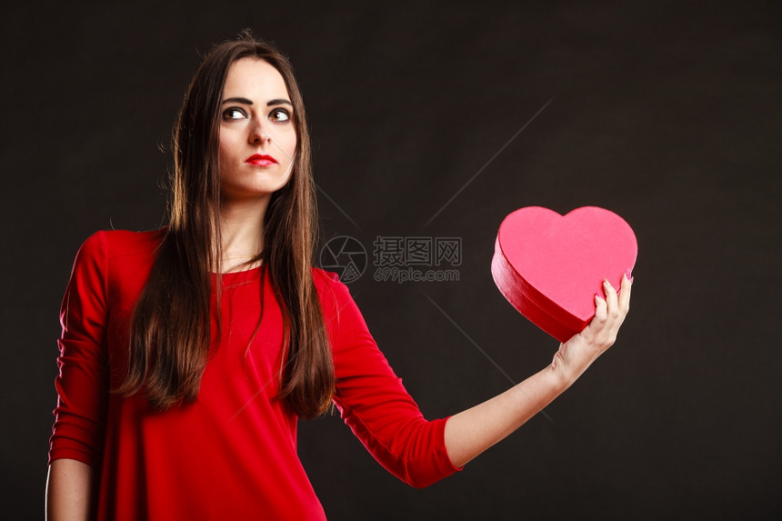 爱和感情穿红衣的年轻美女拿着心箱送礼物在工作室的灰色背景上图片