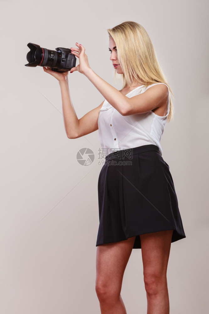 摄影女师拍图像美丽的金发女人带着灰色背景的专业相机图片