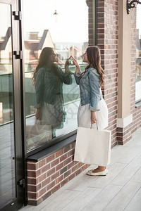 漂亮的女人拿着购物袋看店窗图片