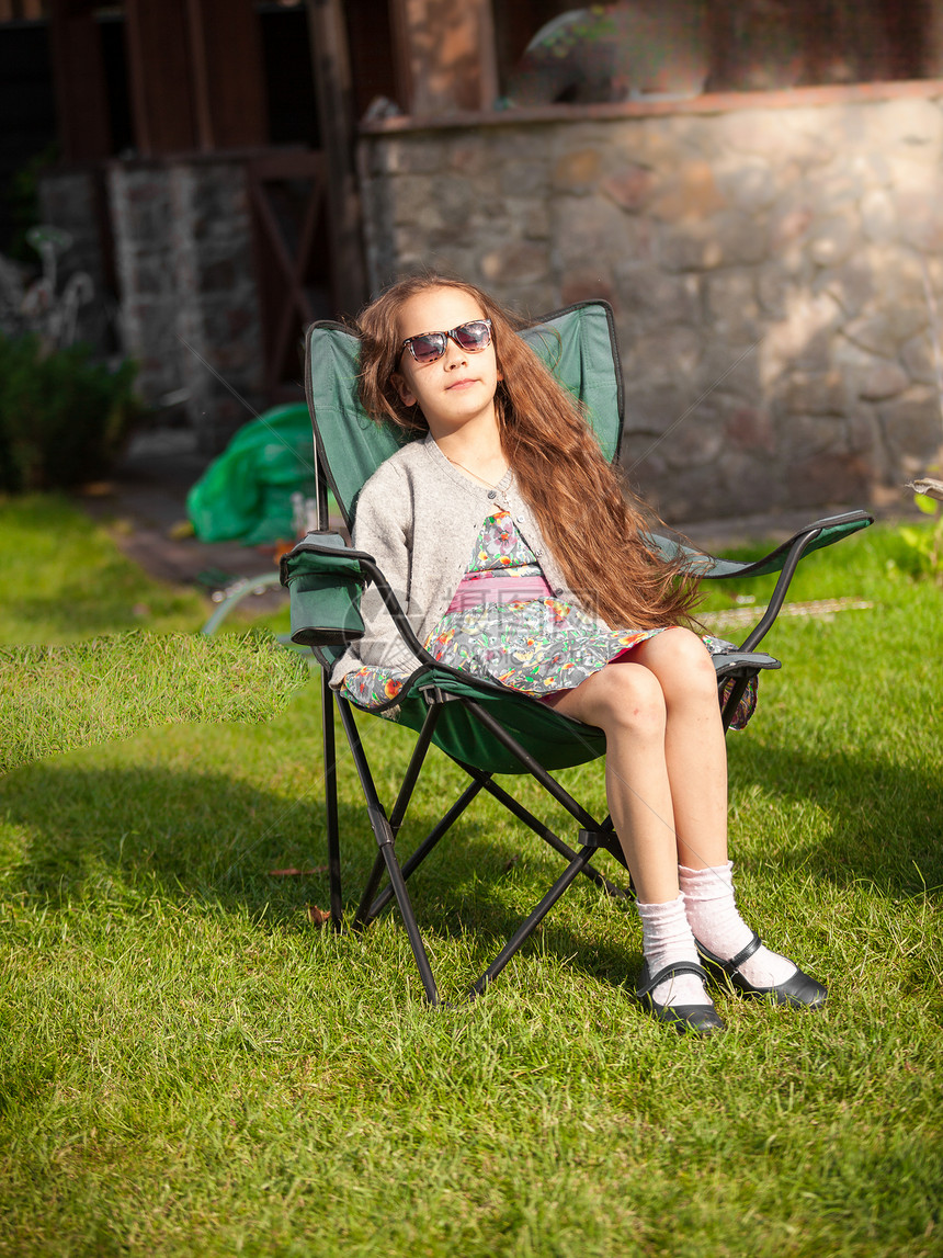 可爱女孩在草地上坐椅子晒日光浴的外门照片图片
