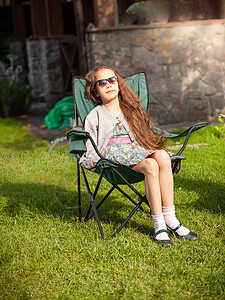 可爱女孩在草地上坐椅子晒日光浴的外门照片图片