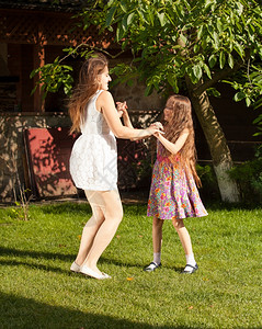 两个姐妹在院子里开派对和在草地上跳舞图片