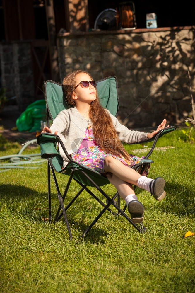 美丽的年轻女孩在阳光明媚的白天在草地上坐椅子放松图片