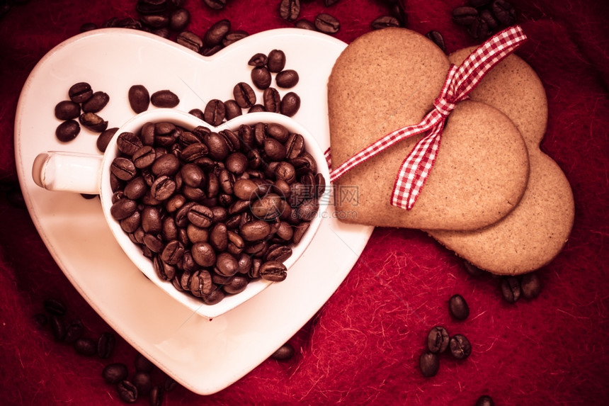 咖啡爱概念心形白杯咖啡豆和甜饼干姜带红布背景的丝图片