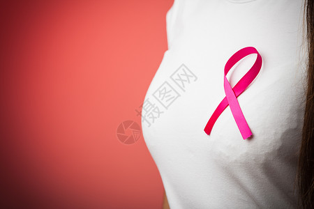 保健医药和乳腺癌认识概念关闭胸前妇女口的粉红色徽章丝带以支持红色乳腺癌病因背景图片