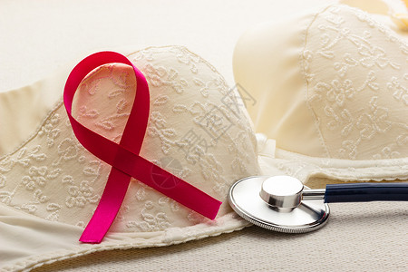 艾滋病女素材保健医药和乳腺癌认识概念在女胸罩上缝合粉色丝带和听诊器背景