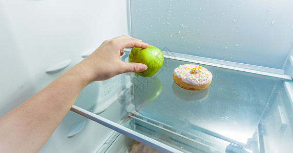 蛋糕冰箱照片手拿苹果而不是甜圈躺在冰箱里背景