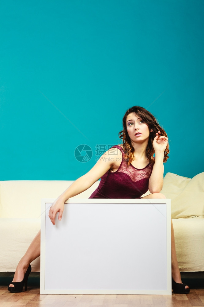 广告概念坐在沙发上空着演示板的优雅年轻女子展示横幅的姑娘签署广告牌复制文本空间图片