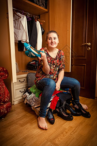 年轻女坐在装满过的手提箱和鞋子上的照片图片