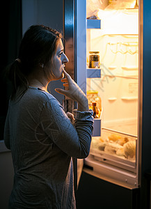 夜深时在冰箱里看年青女人背景图片