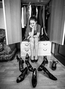 女青年在衣柜中选择鞋子的单色照片图片