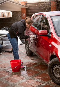 美女在户外用毛巾清洗红色汽车背景图片