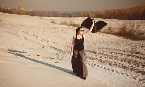 美丽的瘦女人披着黑布在沙漠中摆图片