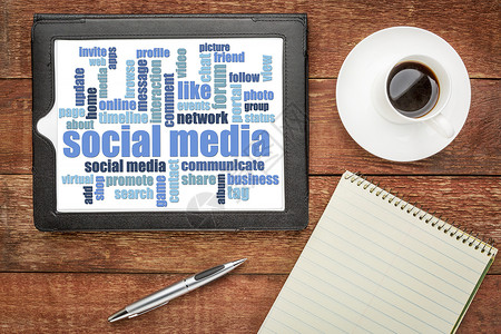 数字平板电脑上的社交媒体文字云带有咖啡和笔记板的古老谷仓桌上顶端视图图片