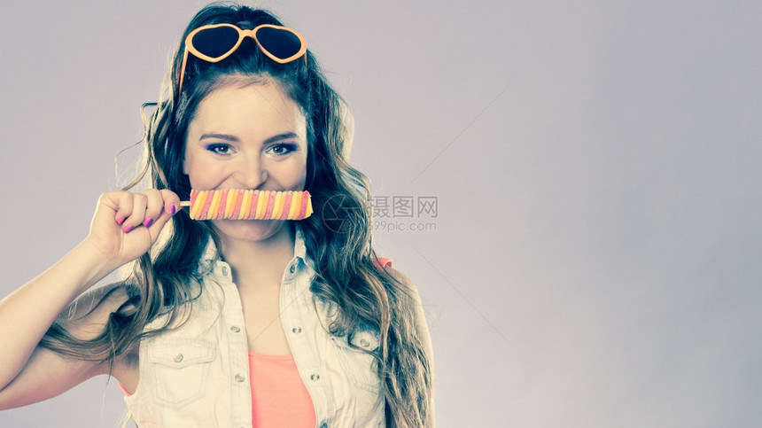 快乐的年轻女模范覆盖嘴唇冰的球过滤器图片