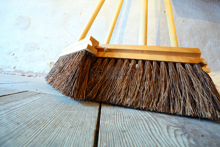 关闭大型扫帚在乡间房屋的老木制地板上做家务图片