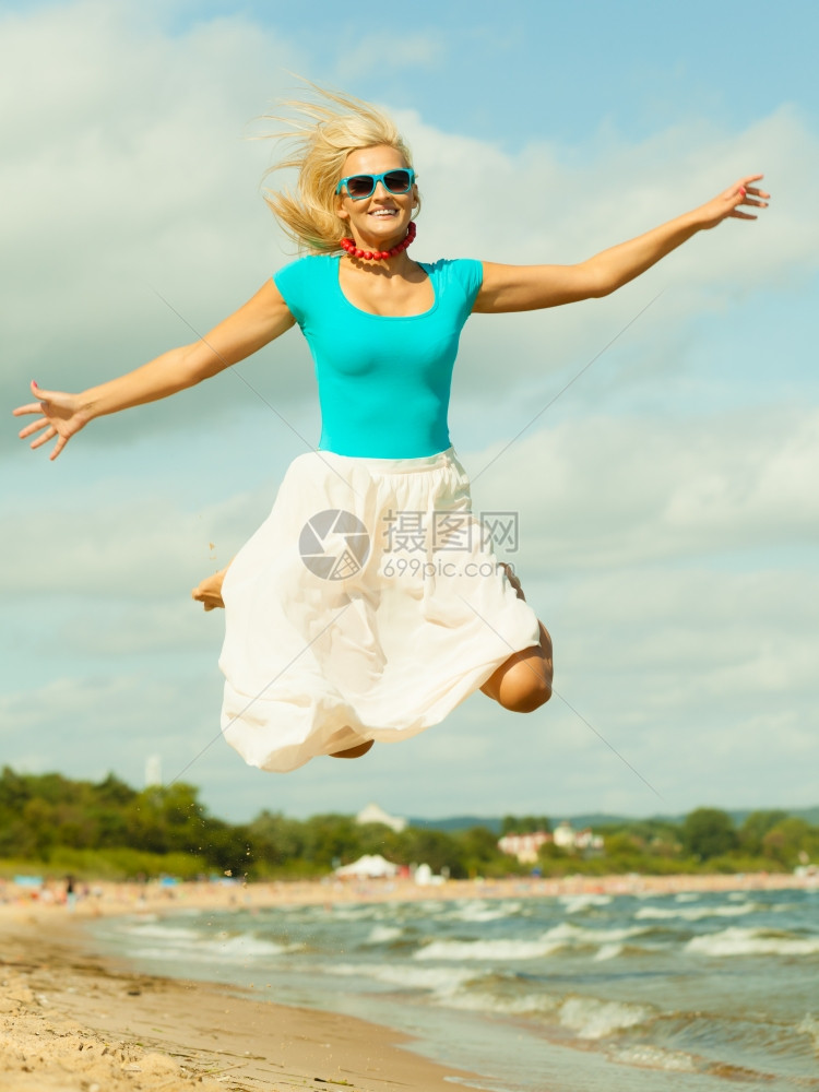 假期旅行和自由概念穿着夏装的漂亮女孩在海滩上跳跃年轻女在海上休闲愉快图片