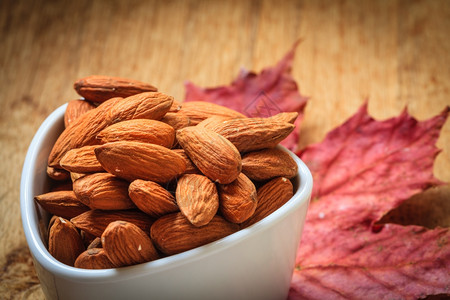 健康食品对心脏健康有好处秋天背景的白碗中杏仁图片