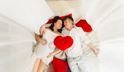 幸福的怀孕夫妇躺在床上与秃天人同共枕的景象图片