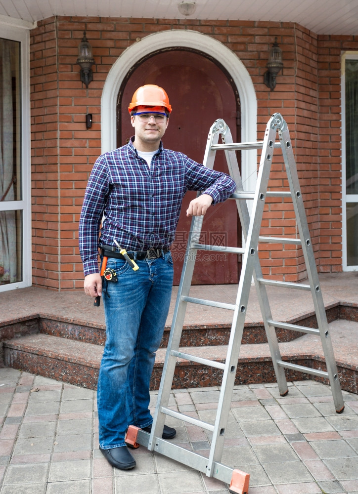 男子头戴盔的建筑工用金属梯子对住家门图片